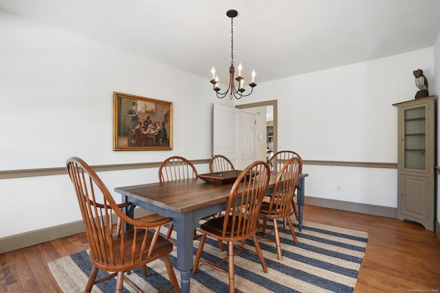 dining area with baseboards, an inviting chandelier, and wood finished floors