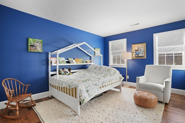 bedroom featuring visible vents, baseboards, and wood finished floors