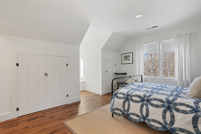 bedroom featuring visible vents, vaulted ceiling, and wood finished floors