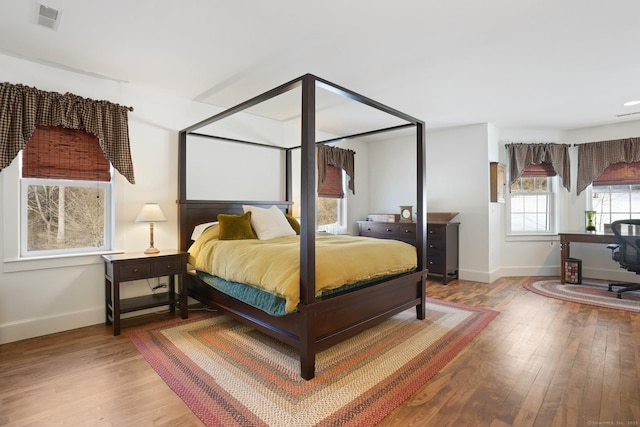 bedroom with visible vents, baseboards, and hardwood / wood-style flooring