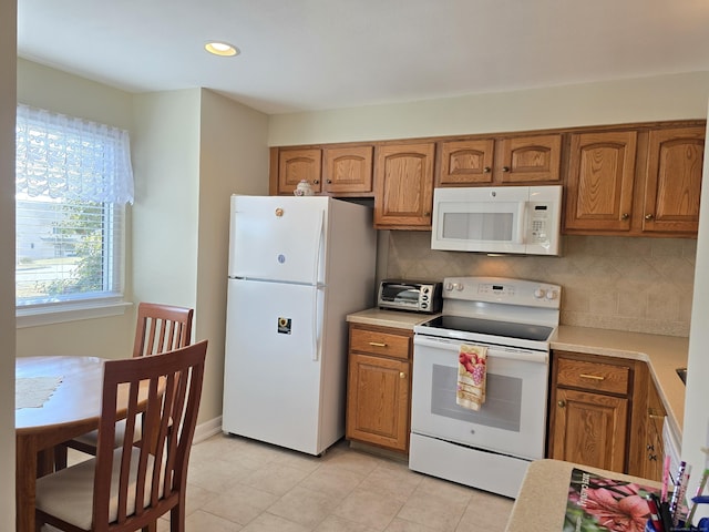 kitchen with tasteful backsplash, light tile patterned floors, and white appliances