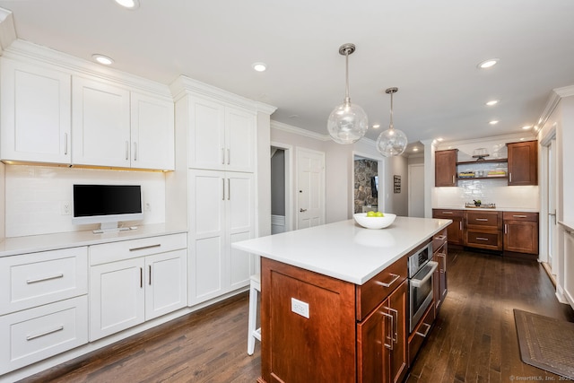 kitchen with pendant lighting, dark wood-type flooring, white cabinetry, backsplash, and a kitchen island