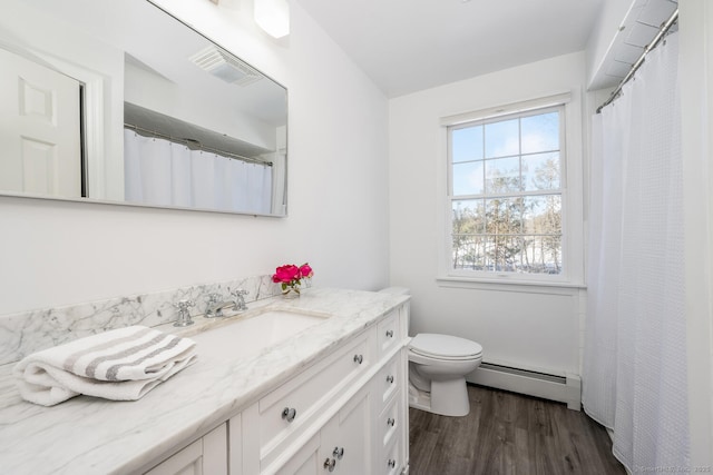 bathroom featuring vanity, wood-type flooring, a baseboard heating unit, and toilet