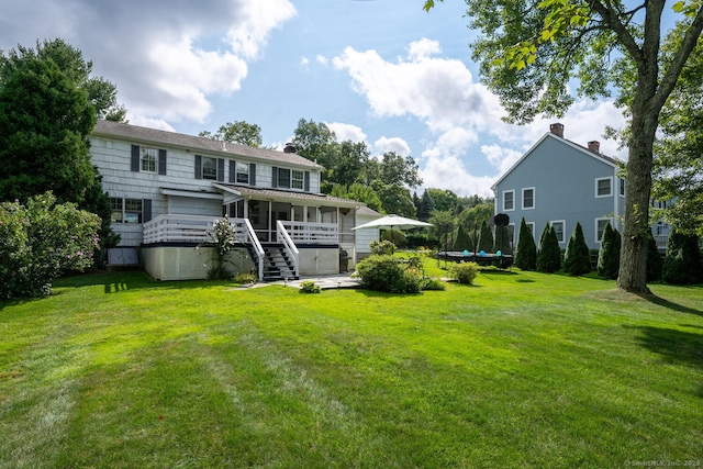 back of property with a trampoline and a lawn