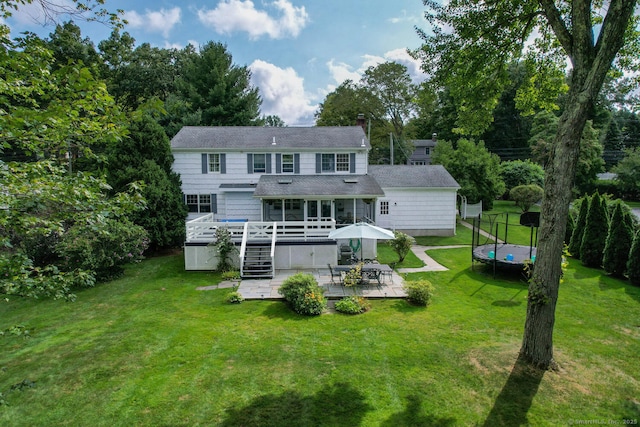 back of house featuring a trampoline, a lawn, a patio, and a deck