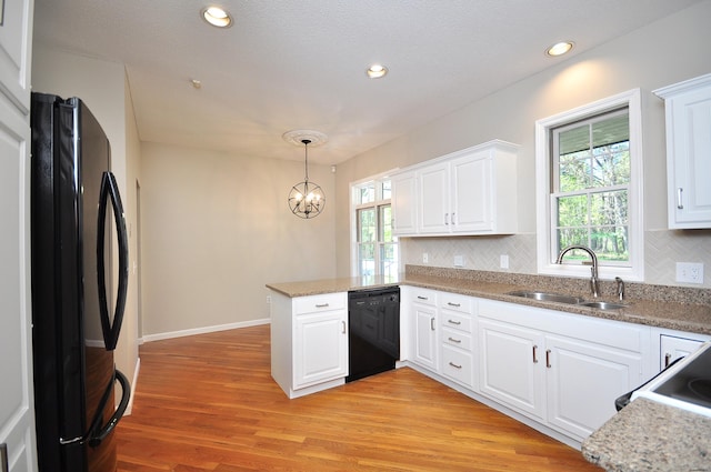 kitchen with a peninsula, white cabinetry, a sink, and black appliances
