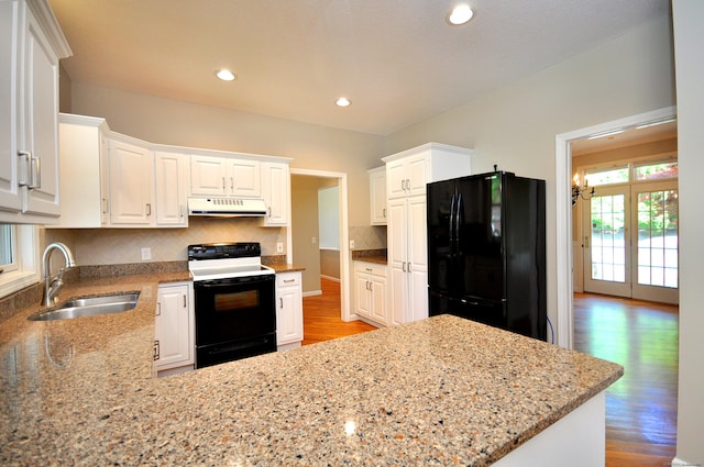 kitchen featuring electric range oven, wood finished floors, a sink, freestanding refrigerator, and under cabinet range hood