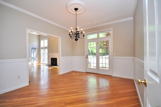 unfurnished dining area with a chandelier, a healthy amount of sunlight, and light wood-style flooring