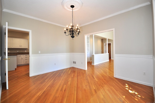 unfurnished dining area with baseboards, a notable chandelier, ornamental molding, and light wood-type flooring
