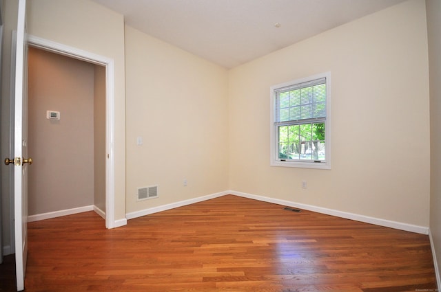 unfurnished room with baseboards, visible vents, and wood finished floors