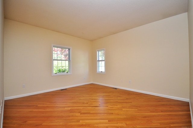 unfurnished room featuring baseboards, visible vents, and light wood-type flooring