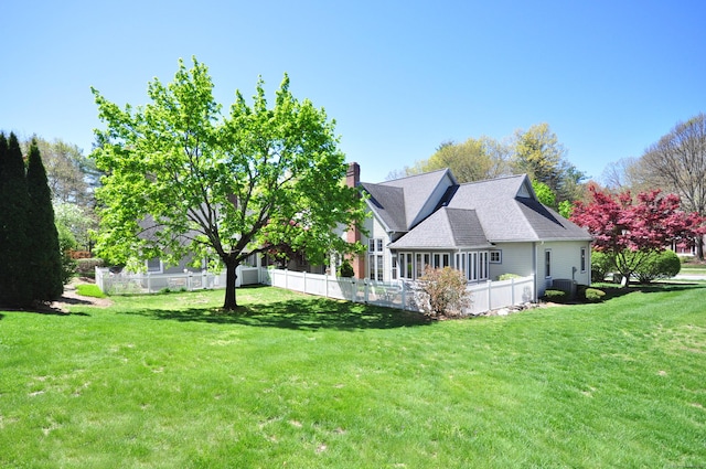 back of house featuring a yard, fence, and a chimney