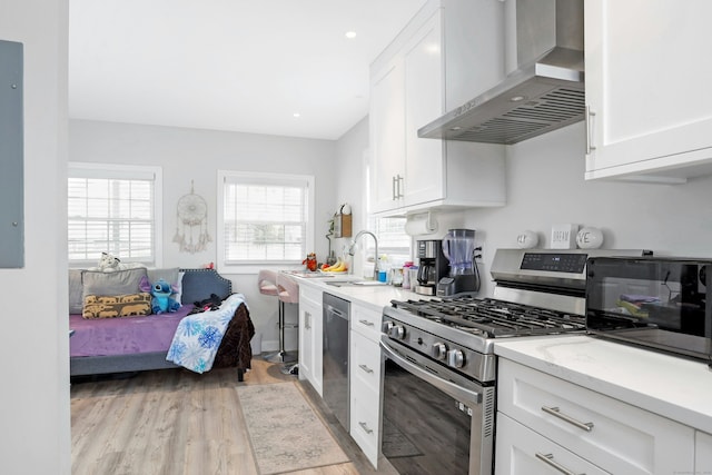 kitchen featuring white cabinets, stainless steel appliances, sink, and wall chimney exhaust hood