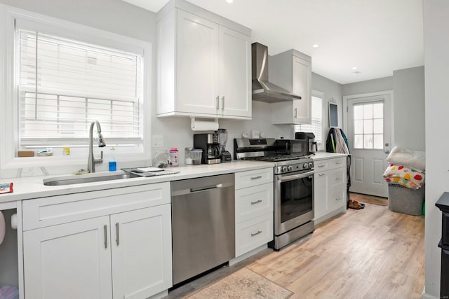 kitchen featuring sink, white cabinets, wall chimney exhaust hood, and appliances with stainless steel finishes