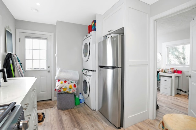 laundry area featuring stacked washer and clothes dryer and light hardwood / wood-style floors