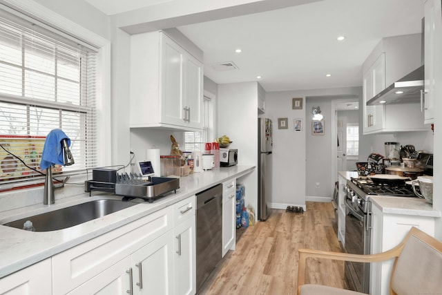 kitchen featuring a healthy amount of sunlight, appliances with stainless steel finishes, sink, and white cabinets