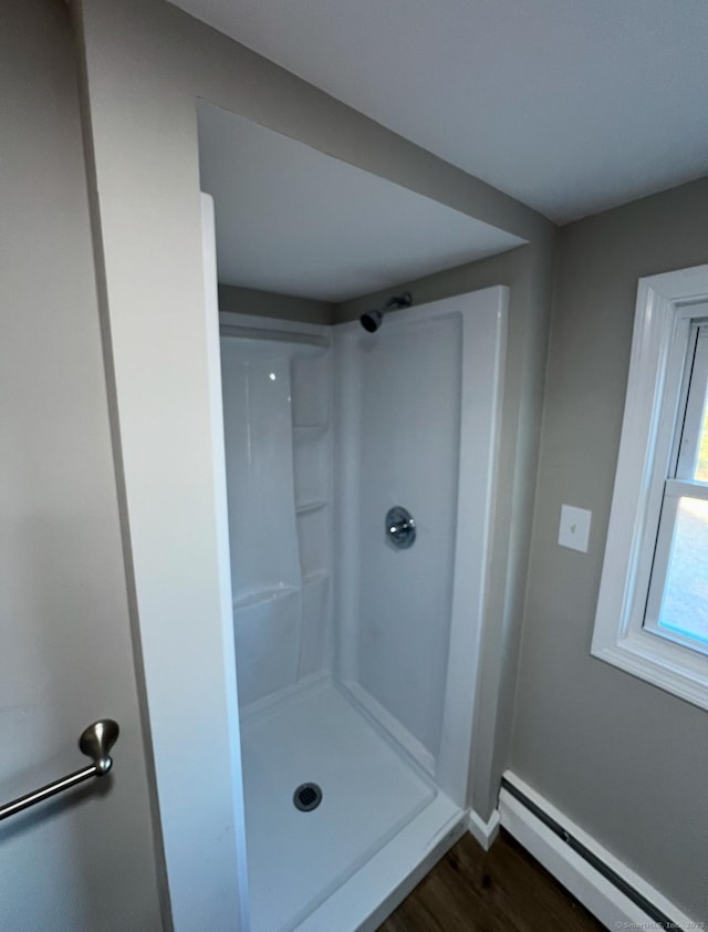 bathroom featuring wood-type flooring, baseboard heating, and a shower