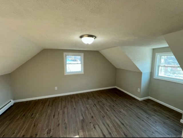 additional living space featuring a textured ceiling, a baseboard heating unit, dark hardwood / wood-style flooring, and lofted ceiling