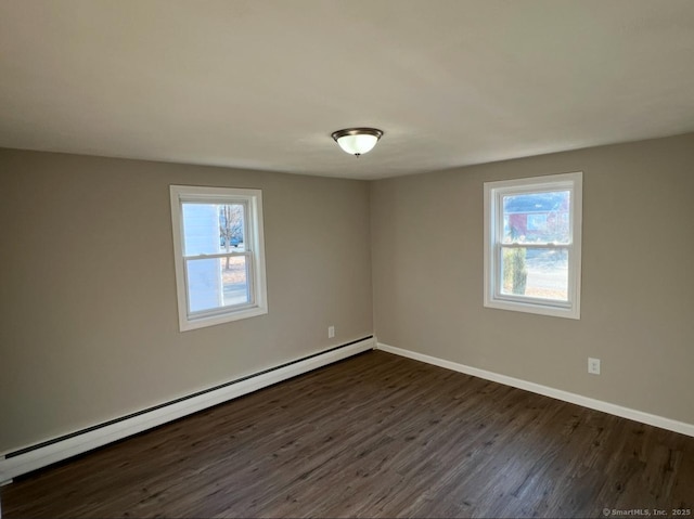 empty room featuring a wealth of natural light, a baseboard radiator, and dark hardwood / wood-style flooring