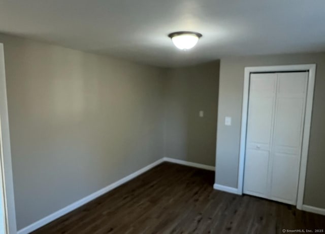 unfurnished bedroom with a closet and dark hardwood / wood-style flooring