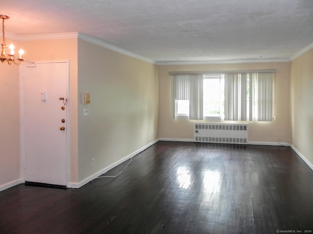 spare room featuring ornamental molding, dark wood-type flooring, radiator heating unit, and an inviting chandelier