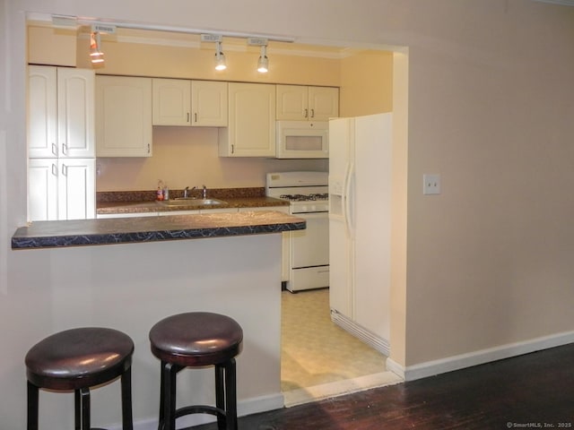 kitchen with sink, white appliances, a kitchen breakfast bar, white cabinets, and kitchen peninsula