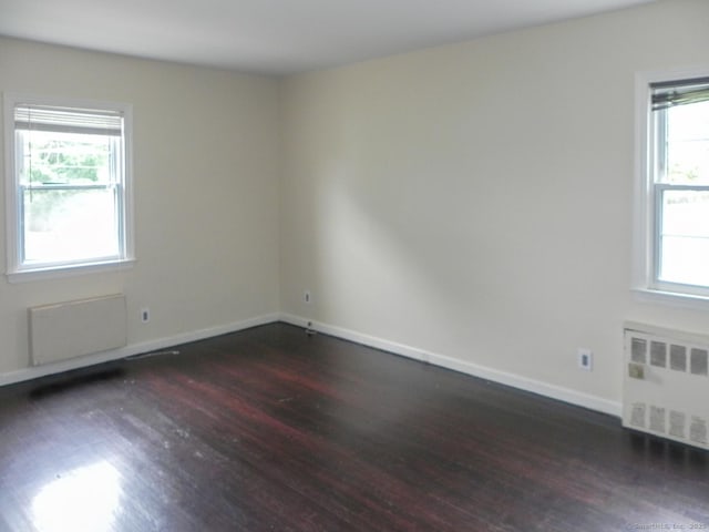 spare room with dark hardwood / wood-style flooring and radiator