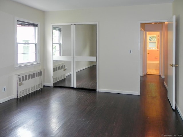 spare room featuring dark hardwood / wood-style floors and radiator