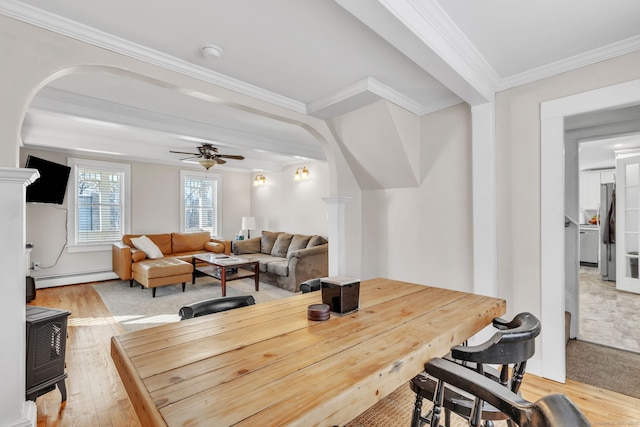 dining room featuring a baseboard heating unit, light hardwood / wood-style flooring, ornamental molding, and ceiling fan