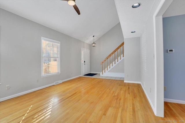 entrance foyer with wood-type flooring, vaulted ceiling, ceiling fan, and a textured ceiling