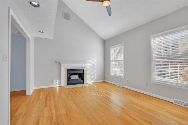 unfurnished living room featuring lofted ceiling, hardwood / wood-style flooring, plenty of natural light, and ceiling fan