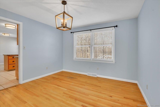 unfurnished room featuring wood-type flooring and a notable chandelier