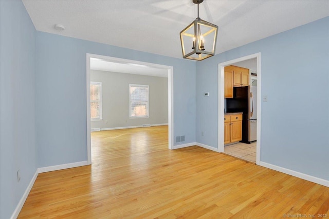 empty room with an inviting chandelier and light wood-type flooring