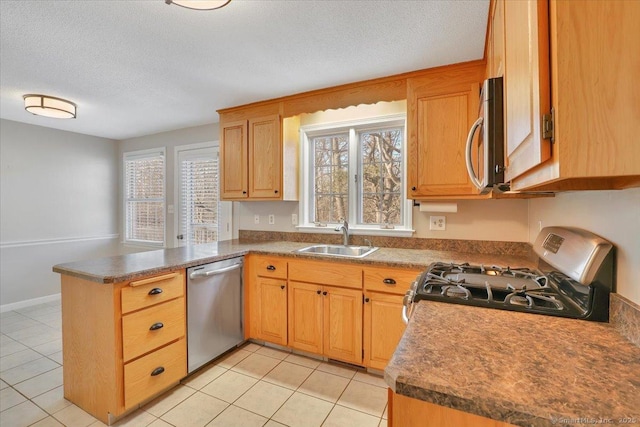 kitchen with appliances with stainless steel finishes, sink, light tile patterned floors, and kitchen peninsula