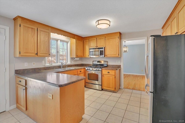 kitchen featuring sink, light tile patterned floors, a textured ceiling, and appliances with stainless steel finishes