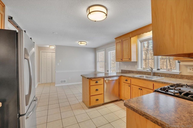 kitchen featuring appliances with stainless steel finishes, sink, light tile patterned floors, kitchen peninsula, and a textured ceiling