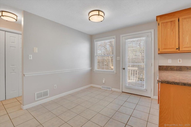 interior space featuring a textured ceiling and light tile patterned floors