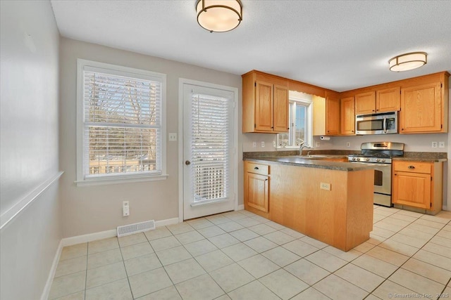 kitchen featuring light tile patterned floors, sink, appliances with stainless steel finishes, a textured ceiling, and kitchen peninsula