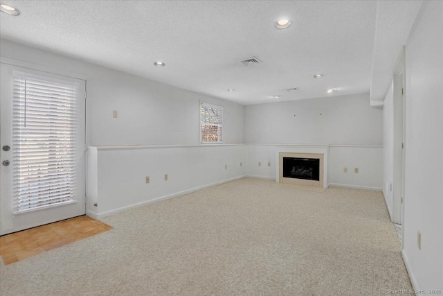 unfurnished living room with light carpet and a textured ceiling