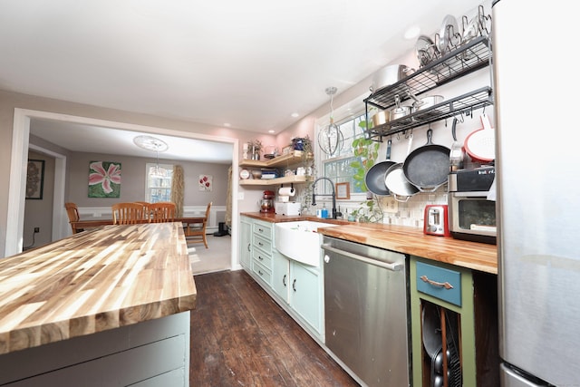 kitchen featuring stainless steel dishwasher, wooden counters, sink, and green cabinetry