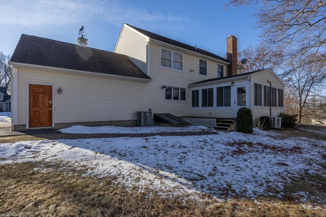 snow covered property featuring a sunroom, ac unit, and central air condition unit