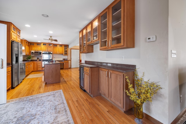 kitchen featuring sink, a kitchen island, stainless steel appliances, beverage cooler, and light hardwood / wood-style floors