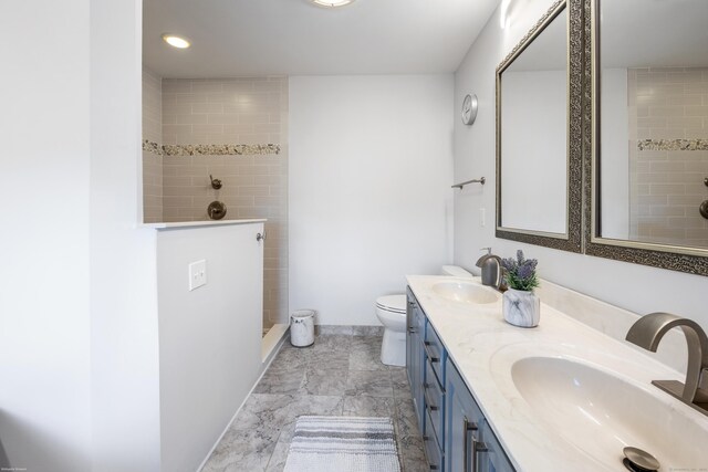 bathroom featuring vanity, toilet, and a tile shower