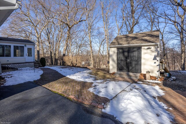 yard covered in snow featuring a garage and an outbuilding