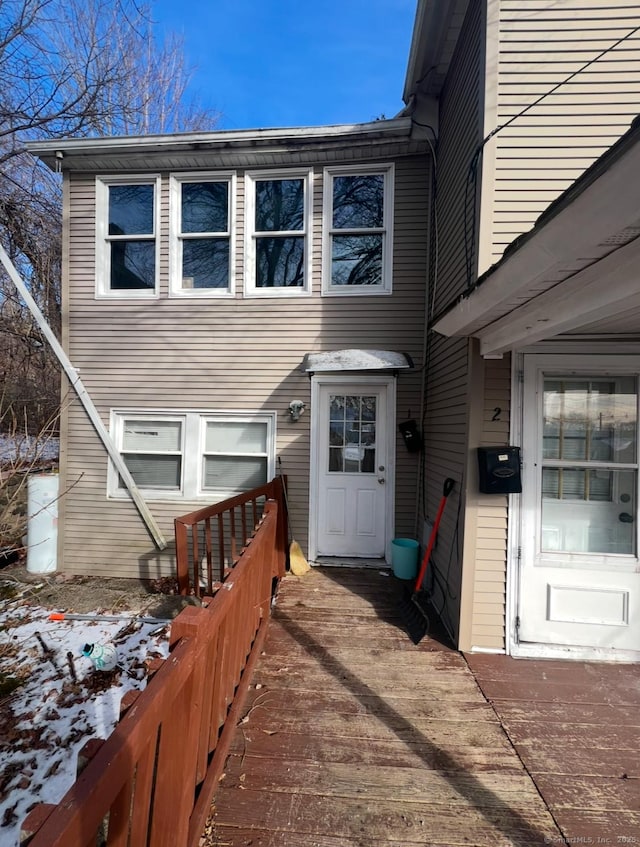 snow covered property entrance featuring a wooden deck