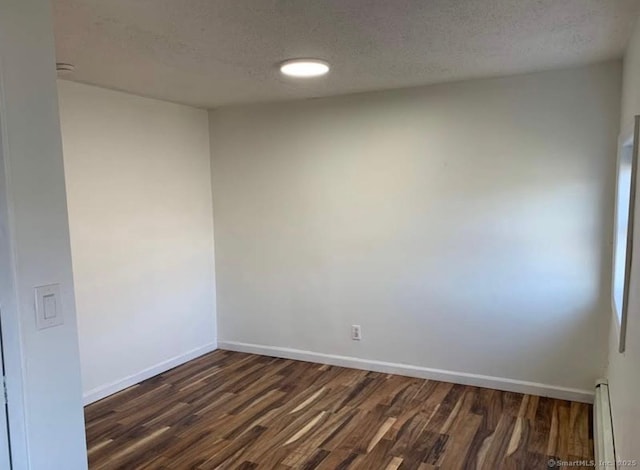 empty room with a textured ceiling, a baseboard heating unit, and dark hardwood / wood-style flooring