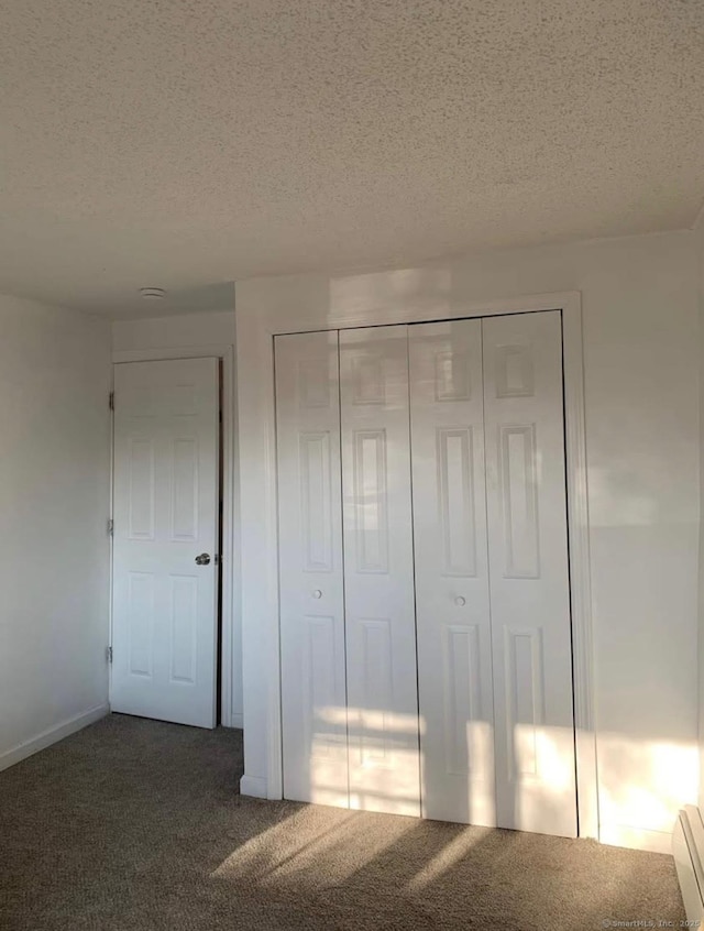 unfurnished bedroom featuring a closet, dark carpet, and a textured ceiling