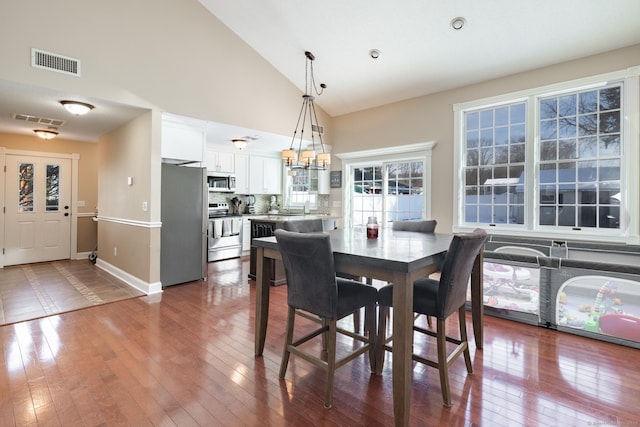 dining room featuring hardwood / wood-style flooring, a chandelier, and high vaulted ceiling