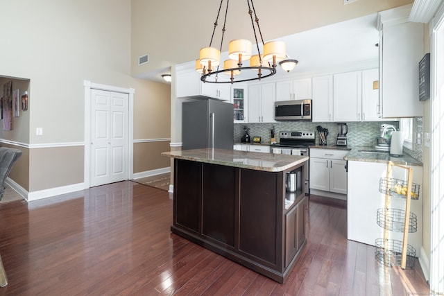 kitchen featuring light stone countertops, decorative light fixtures, stainless steel appliances, and a kitchen island