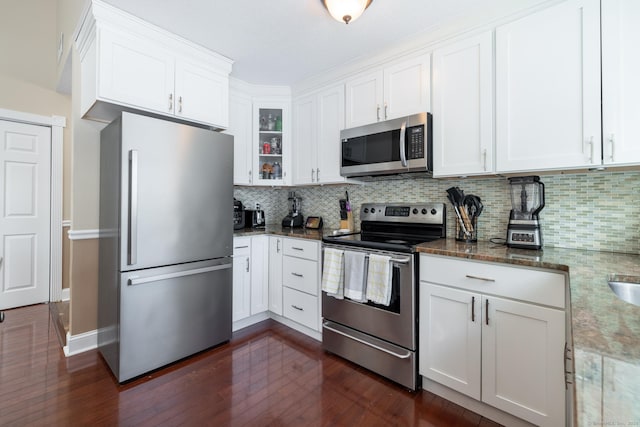 kitchen featuring tasteful backsplash, appliances with stainless steel finishes, white cabinets, and dark stone counters